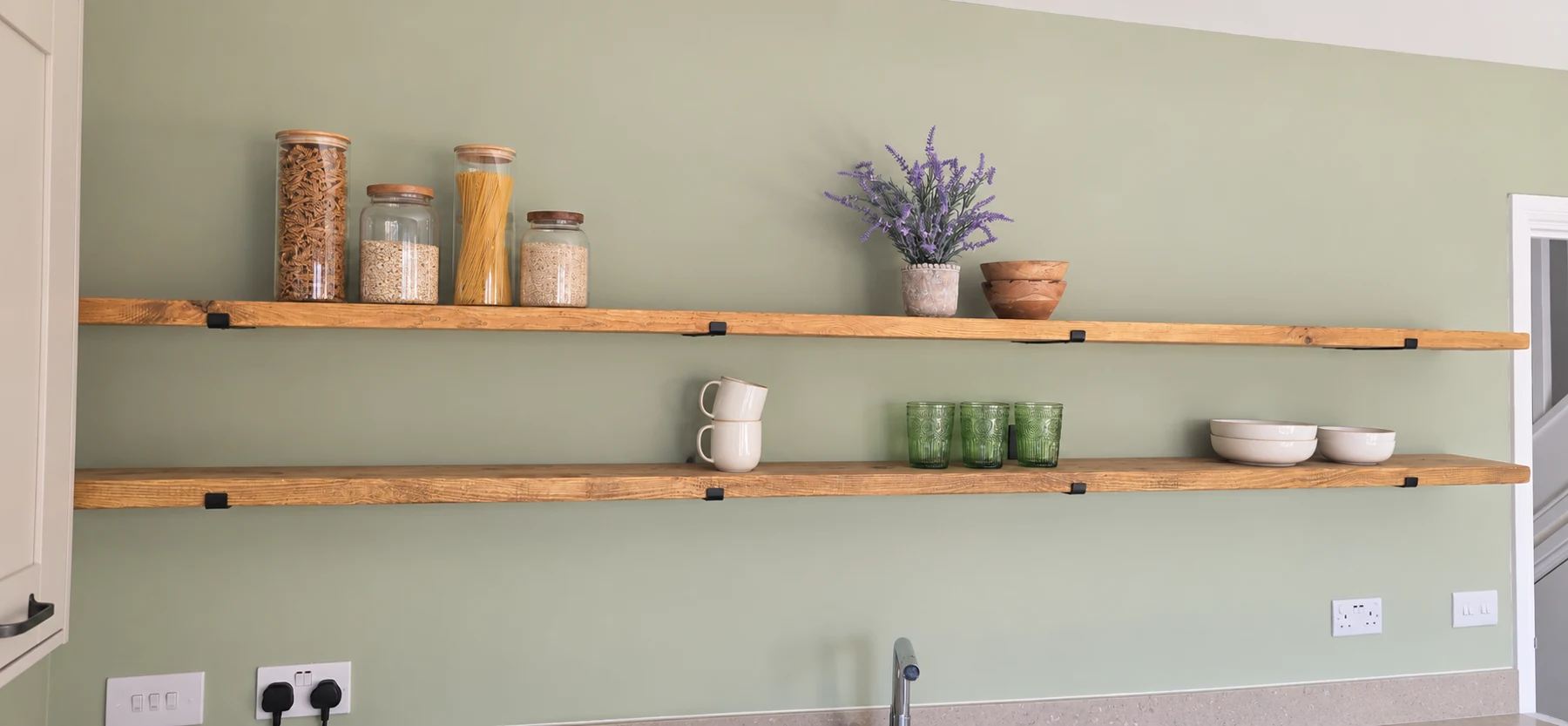 Handmade wooden kitchen shelves on a green wall